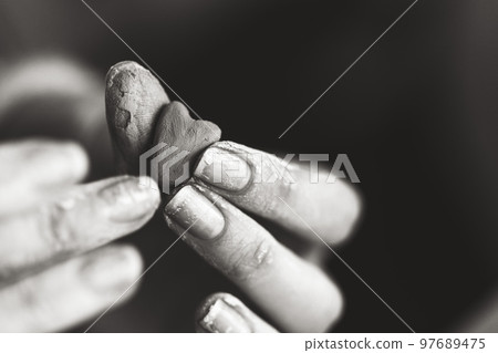 Heart made of potter's clay in the hands of a master potter. Love concept. Black and white color Heart made of potter's clay in the hands of a master potter. Love concept. Black and white color 97689475