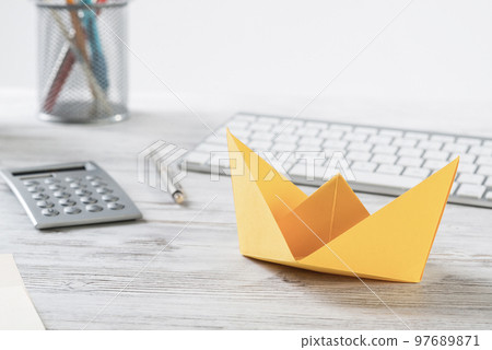 Workspace with office desk and yellow paper ship 97689871