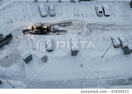 Tractor loader machine uploading dirty snow into dump truck. Tractor loader machine uploading dirty snow into dump truck. 97689933