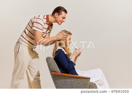 Love and care. Young, beautiful, stylish couple in vintage style fashion clothes posing isolated over light background. Retro fashion, relationship, family 97691050