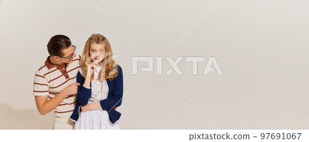 Flyer. Emotional young, beautiful, stylish couple in vintage style fashion clothes posing isolated over light background. 60s, 70s american culture concept 97691067