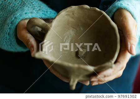 Woman potter in apron molding clay cup.Hands of professional ceramist create pottery crockery at workplace. Craftsmanship hobby.Small business with ceramics master classes education or handmade shop. 97691302