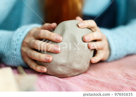 Female pottery artist preparing clay for molding. Close Up view of woman hands with clay. Creative handmade craft. Ceramic studio Female pottery artist preparing clay for molding. Close Up view of woman hands with clay. Creative handmade craft. Ceramic studio 97691635