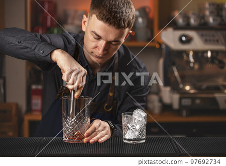 Young bartender using steel madler Young bartender using steel madler 97692734