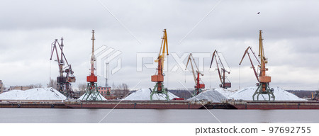 River port in winter. Port cranes on the bank of the river. River port in winter. Port cranes on the bank of the river. 97692755
