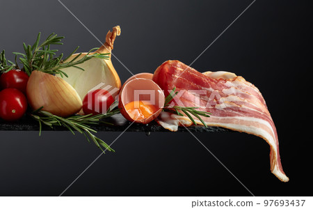 Smoked bacon with eggs, tomatoes, onions and rosemary. 97693437