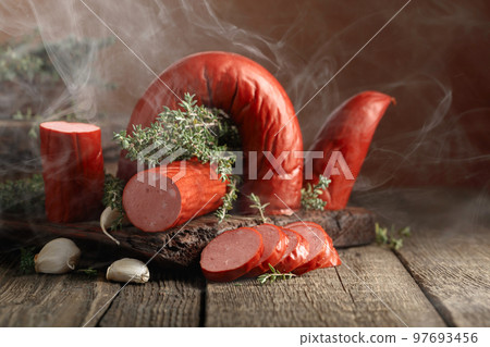 Smoked sausage with thyme and garlic on a wooden table. Smoked sausage with thyme and garlic on a wooden table. 97693456