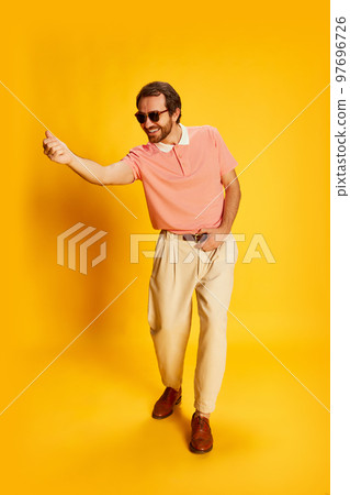 Portrait of stylish man smiling and gesturing isolated over yellow background. Retro style fashion, happiness, ad, sales 97696726