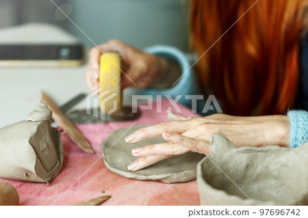 Women's hands knead the clay and sculpt a cup or bowl from it. The process of manufacturing a ceramic product,close up 97696742