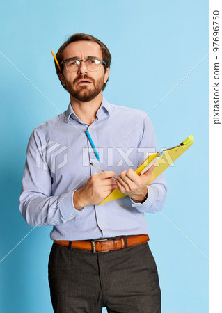 Thoughtful mature man, businessman in office dress code making notes at notebook over blue background. Human emotions, work, mental health Thoughtful mature man, businessman in office dress code making notes at notebook over blue background. Human emotions, work, mental health 97696750