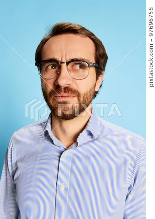 Half-length portrait of mature bearded man in eyewear expressing vivid emotions on his face isolated over blue background. Business, mental health, emotions concept Half-length portrait of mature bearded man in eyewear expressing vivid emotions on his face isolated over blue background. Business, mental health, emotions concept 97696758