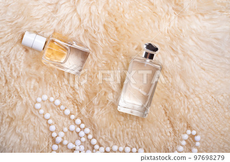 fragrance bottles with necklace at sheepskin fur. glamour concept. flat lay fragrance bottles with necklace at sheepskin fur. glamour concept. flat lay 97698279