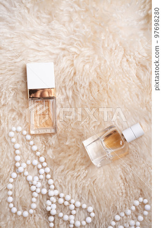 fragrance bottles with necklace at sheepskin fur. glamour concept. flat lay fragrance bottles with necklace at sheepskin fur. glamour concept. flat lay 97698280