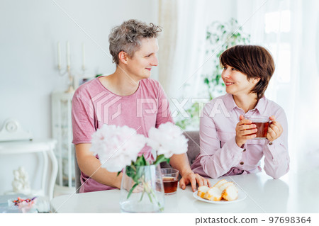 Smiling young man and woman having Breakfast And having fun together at home kitchen with light interior background. Family time. Happy couple in love enjoying each other at their home. 97698364