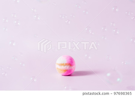 Spa concept. Aromatic Pink bath bomb on the pink background with flying soap bubbles. Selective focus, copy space 97698365