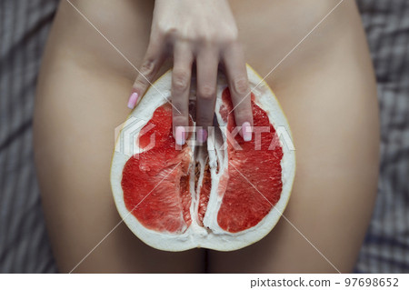 Sex and female masturbation. A lies on a bed between Pamela's legs. Grapefruit symbolizes the female vagina that is caressed by the fingers 97698652