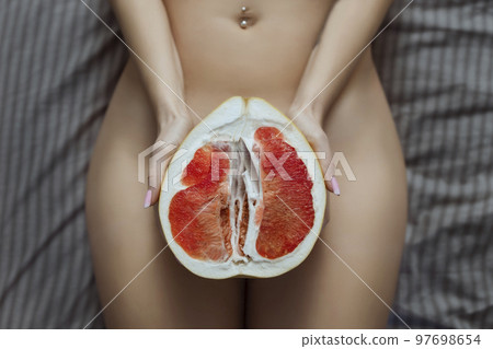 A naked girl holds a grapefruit symbol of the vagina in her hands. Intimate rejuvenation and epilation of the bikini area A naked girl holds a grapefruit symbol of the vagina in her hands. Intimate rejuvenation and epilation of the bikini area 97698654