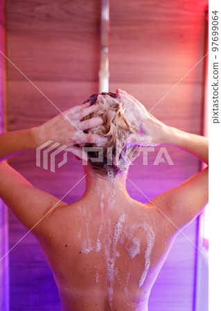 Beautiful woman washes her hair in the shower 97699064