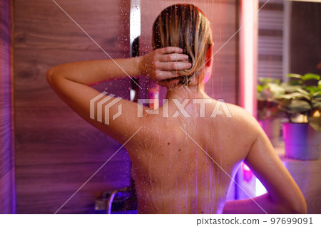 Beautiful woman washes her hair in the shower 97699091
