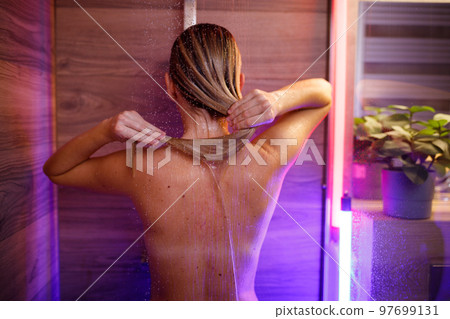 Beautiful woman washes her hair in the shower 97699131