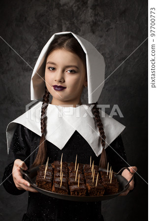 Gothic girl with pigtails in a cap holds a tray with chocolate cake 97700773