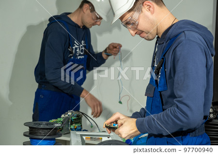 Electricians work in workshop with cables for charging plug 97700940