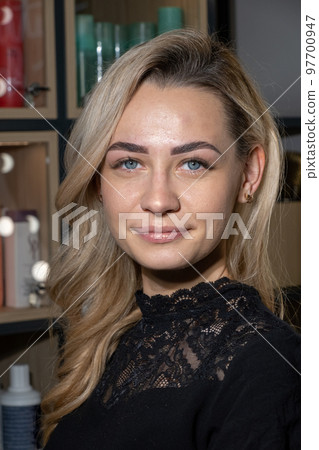 Blonde woman with tinted eyebrows and lash extensions smiles Blonde woman with tinted eyebrows and lash extensions smiles 97700947