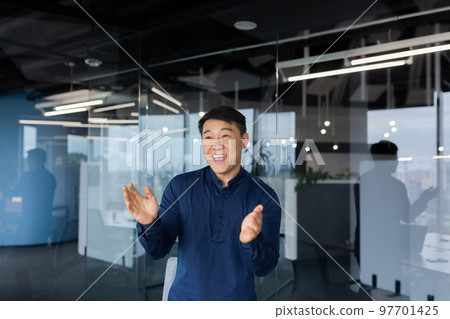 Young man Asian businessman, employee dancing in the office, celebrating victory, successful deal, monetary reward, promotion. He smiles, claps his hands. Young man Asian businessman, employee dancing in the office, celebrating victory, successful deal, monetary reward, promotion. He smiles, claps his hands. 97701425