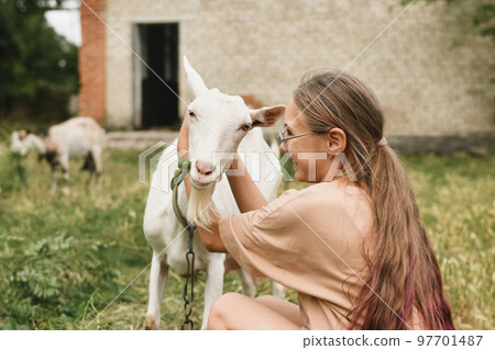 A girl hugging her white goat as a friend in the village 97701487