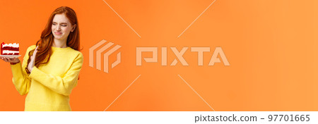 No thanks, dont want. Cute redhead girl trying resist temptation take bite delicious sweets, holding tasty cake and showing stop, refusal or rejection with grimacing face, express aversion, dislike 97701665