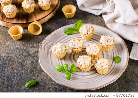 Mini tartlets with a salad of eggs, canned fish and mayonnaise on a plate. Homemade snacks Mini tartlets with a salad of eggs, canned fish and mayonnaise on a plate. Homemade snacks 97701758