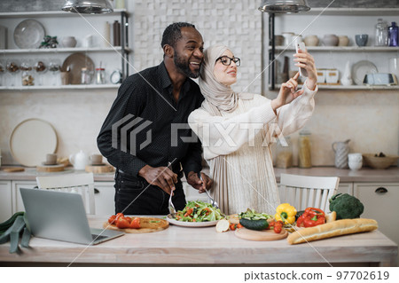 Cute multinational couple taking selfie or having video conversation with friends 97702619