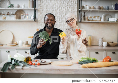 Attractive african american man and muslim young woman cooking dinner together Attractive african american man and muslim young woman cooking dinner together 97702747