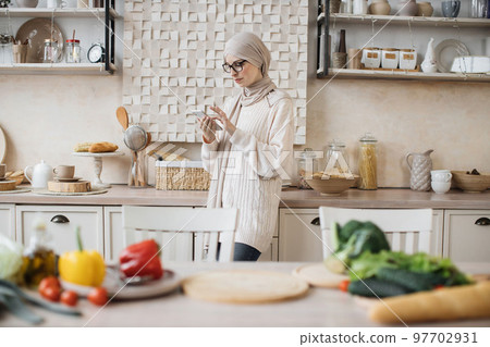 Attractive muslim woman preparing romantic dinner on home kitchen. Attractive muslim woman preparing romantic dinner on home kitchen. 97702931