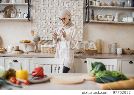 Attractive muslim woman preparing romantic dinner on home kitchen. Attractive muslim woman preparing romantic dinner on home kitchen. 97702932