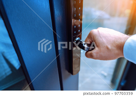 Male hand holding a handle of key free smart lock. Keyless access to home or hotel. 97703359