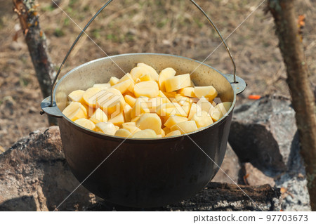 Sliced potato in a cauldron. Food preparing on an open fire Sliced potato in a cauldron. Food preparing on an open fire 97703673