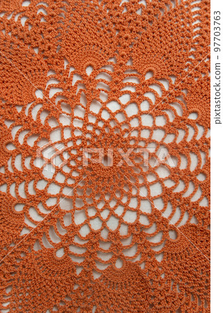Openwork napkin for decor on white background. Bright orange crocheted product. Knitted lace pattern. Vertical frame Openwork napkin for decor on white background. Bright orange crocheted product. Knitted lace pattern. Vertical frame 97703763