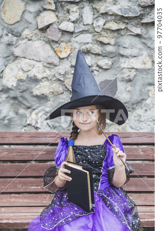 young sorceress thinking with a magic wand and a book of spells young sorceress thinking with a magic wand and a book of spells 97704035