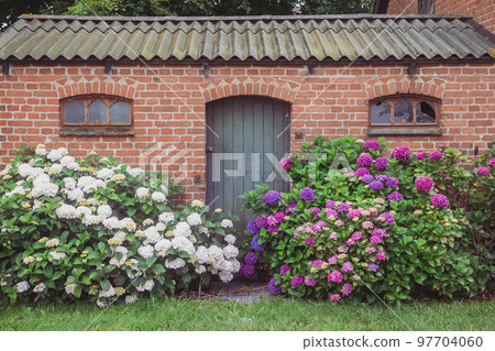 Old brick house with a large flower bed 97704060