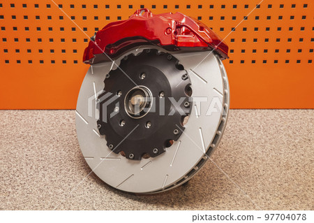 steel brake disc and red sports support on the table in the workshop steel brake disc and red sports support on the table in the workshop 97704078
