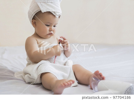 beautiful baby with towel on her head looks at eyeliner for eyelids  97704186