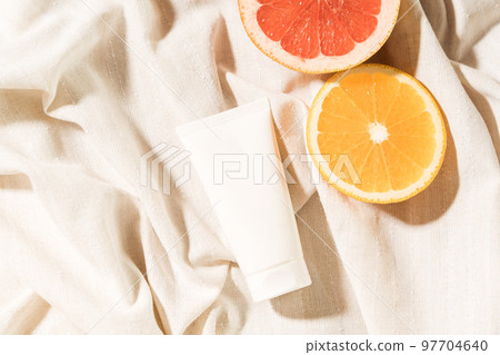 Empty white cream tube mockup (unbranded) and citrus slices lying on a cotton cloth. 97704640