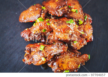 fried chicken with garlic and sesame in caramel on a black tray. fried chicken with garlic and sesame in caramel on a black tray. 97704857