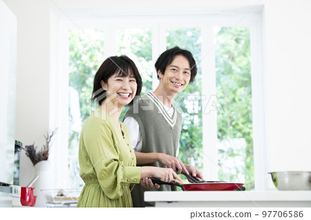 A young couple cooking, looking at the camera 97706586