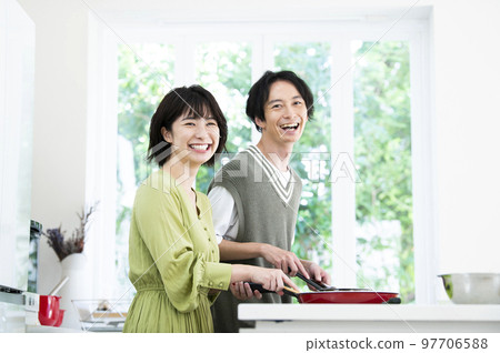 A young couple cooking, looking at the camera 97706588