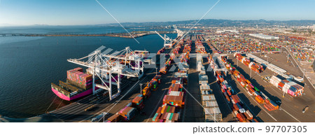 The Oakland Outer Harbor aerial view. Loaded trucks moving by Container cranes. View of busy Port of Oakland. Shipping terminal facility. 97707305