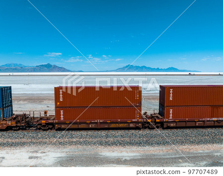 Cargo train passing by the desert Nevada, USA near Salt Flats. A railroad car is a vehicle used for the carrying of cargo on a railway. Cargo train passing by the desert Nevada, USA near Salt Flats. A railroad car is a vehicle used for the carrying of cargo on a railway. 97707489