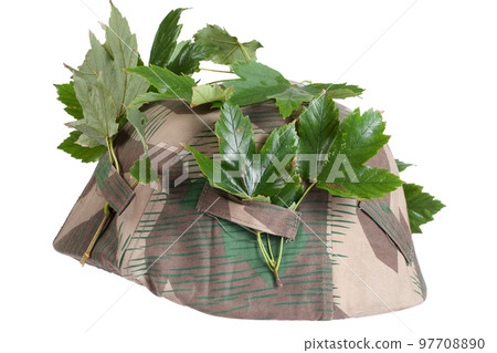 German Nazi Army steel helmet camouflaged with cover and tree leaves. World War II period 1933-1945. 97708890
