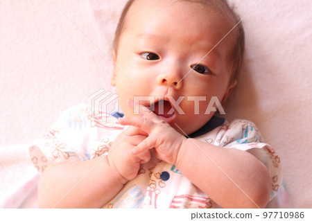 3個月大的嬰兒看著他的手 3個月大的嬰兒看著他的手 97710986